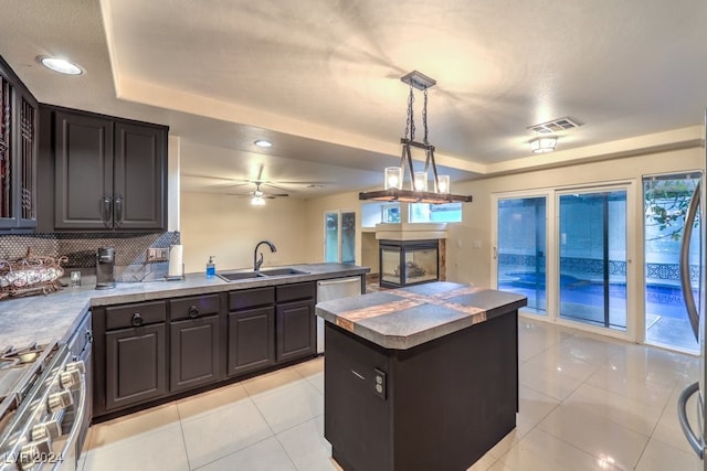 kitchen featuring stainless steel appliances, sink, a kitchen island, backsplash, and decorative light fixtures