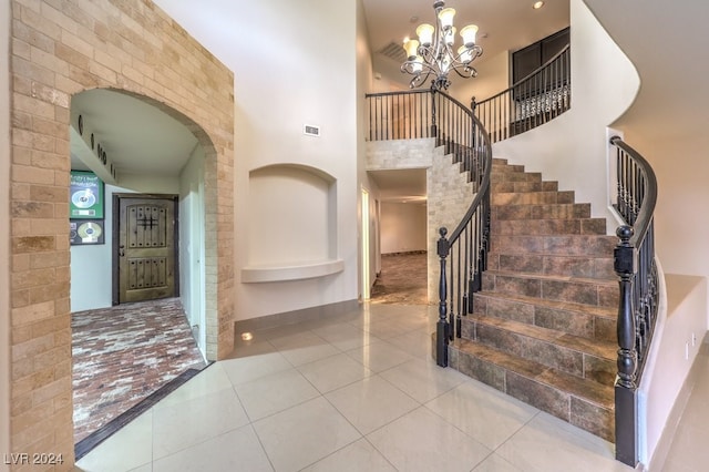 foyer entrance with a high ceiling, a chandelier, and tile patterned floors