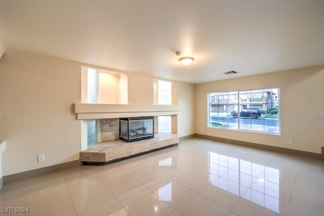 unfurnished living room with a brick fireplace and tile patterned floors