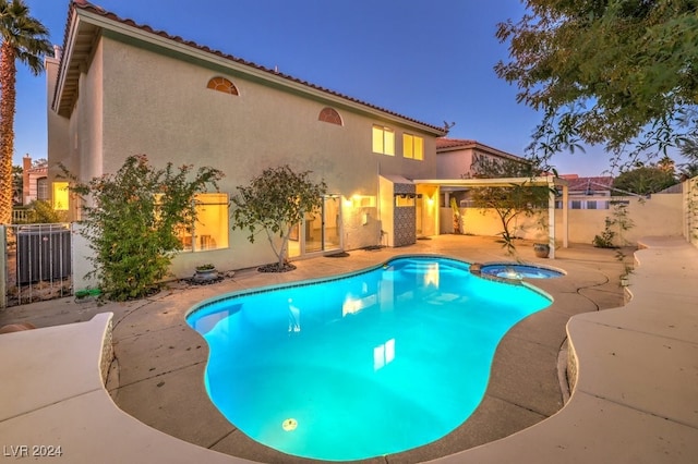 pool at dusk with central air condition unit, a patio area, and an in ground hot tub