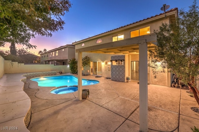 pool at dusk featuring a pergola, a patio, and an in ground hot tub