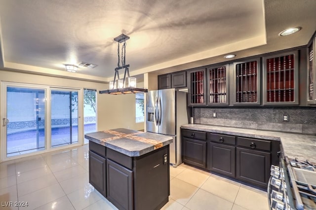 kitchen featuring backsplash, decorative light fixtures, dark brown cabinets, stainless steel refrigerator with ice dispenser, and a center island