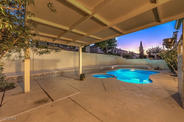 pool at dusk with a patio area