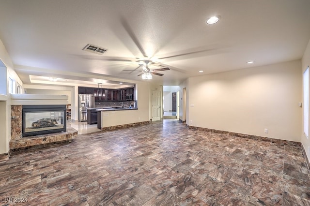 unfurnished living room featuring sink and ceiling fan