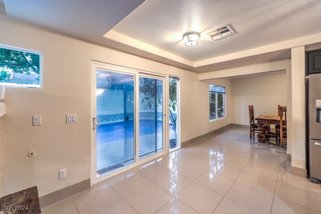 interior space with plenty of natural light, a textured ceiling, and a raised ceiling