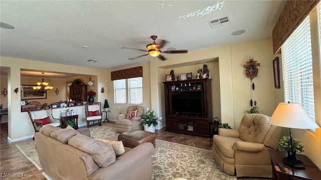 living room featuring ceiling fan with notable chandelier, wood-type flooring, and a textured ceiling