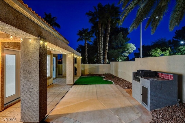 patio at night featuring area for grilling