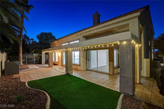 back house at twilight featuring a patio