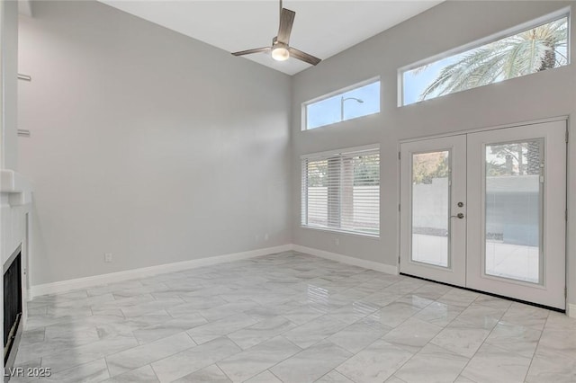 unfurnished living room with french doors, ceiling fan, and a high ceiling