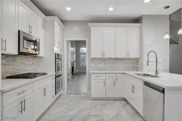 kitchen with pendant lighting, sink, white cabinets, kitchen peninsula, and stainless steel appliances