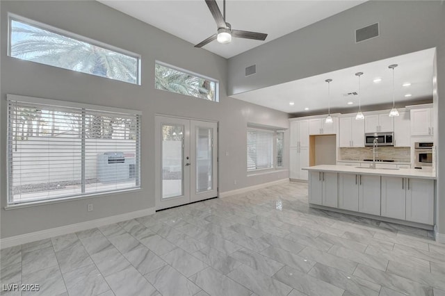 kitchen featuring french doors, decorative light fixtures, appliances with stainless steel finishes, white cabinets, and backsplash