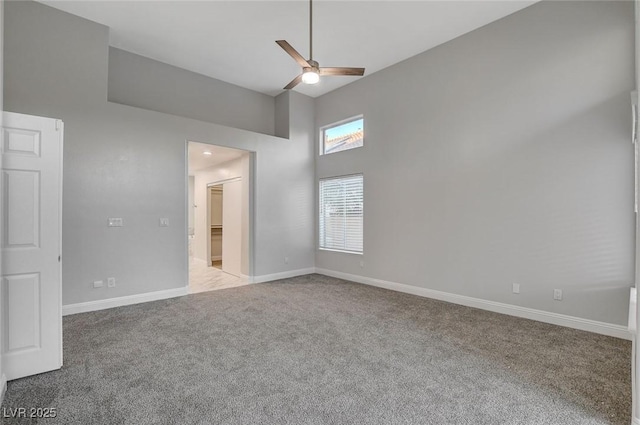 spare room featuring a high ceiling, light carpet, and ceiling fan