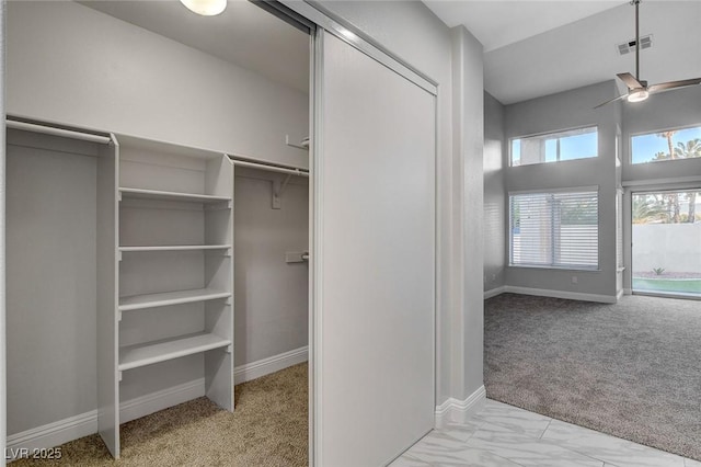 walk in closet with ceiling fan and light colored carpet