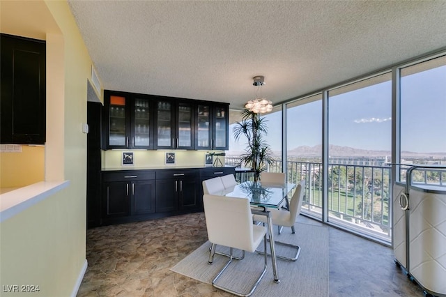 dining room featuring a mountain view, a textured ceiling, a wall of windows, and a notable chandelier