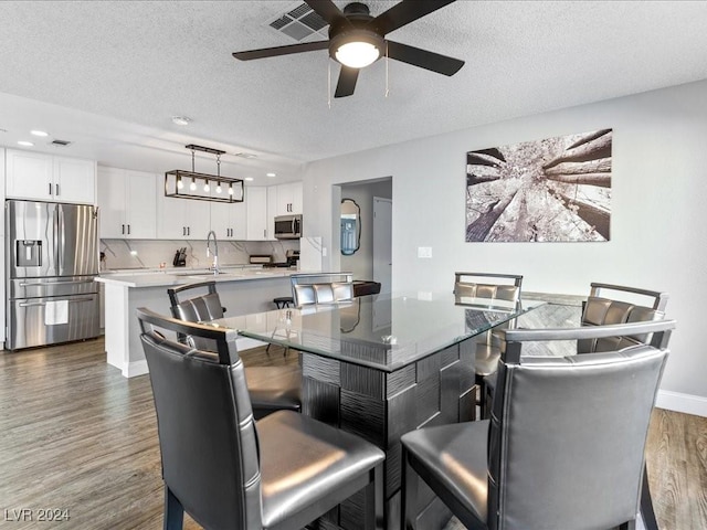 dining area featuring ceiling fan, dark wood-type flooring, a textured ceiling, and sink