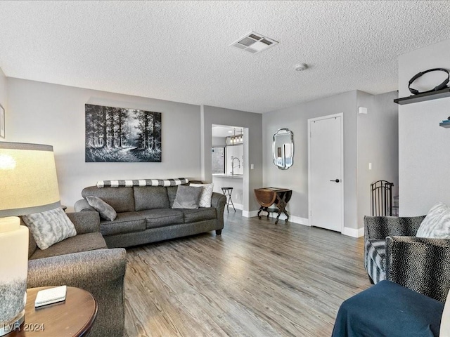 living room with hardwood / wood-style flooring, sink, and a textured ceiling