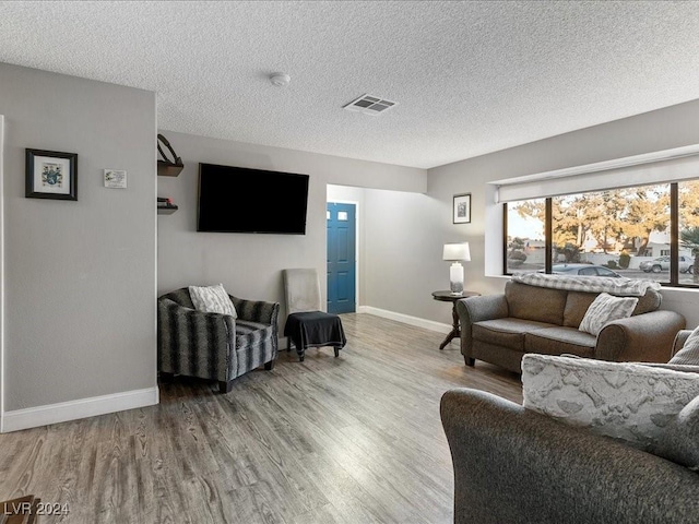 living room featuring light wood-type flooring and a textured ceiling