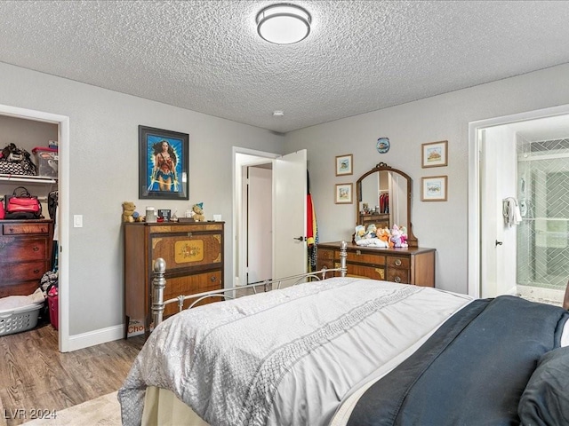 bedroom featuring a closet, a spacious closet, a textured ceiling, and light hardwood / wood-style floors