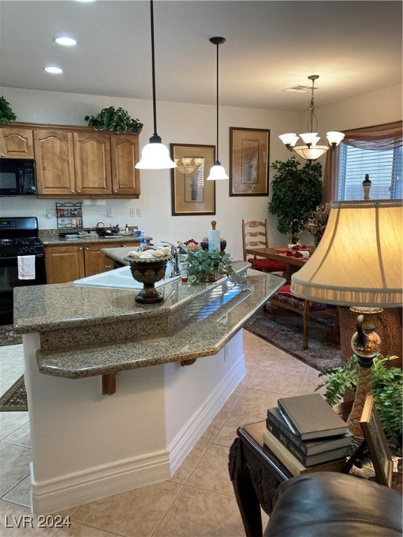 kitchen featuring black appliances, hanging light fixtures, and a breakfast bar