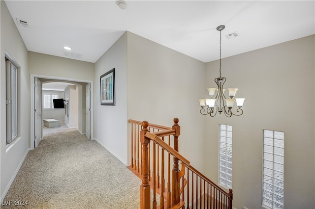 hallway featuring carpet flooring and an inviting chandelier