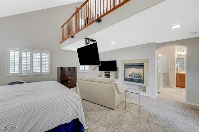 bedroom with a fireplace, ensuite bath, and light carpet