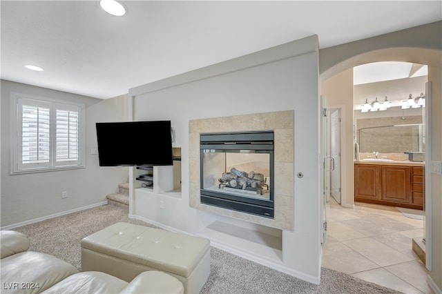 living room featuring a tiled fireplace, sink, and light carpet