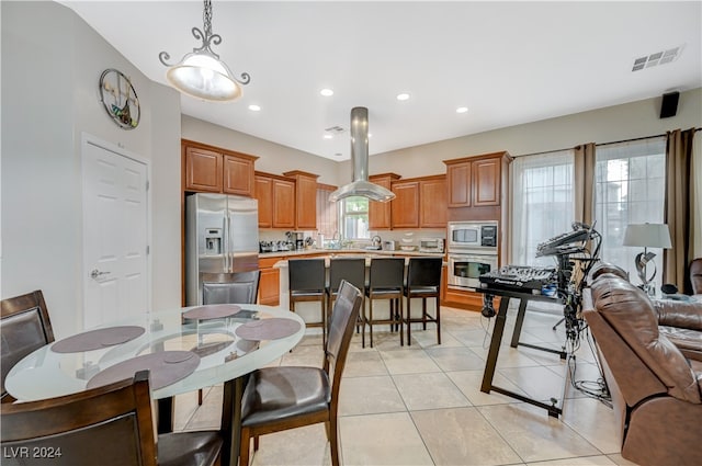 kitchen with stainless steel appliances, a wealth of natural light, decorative light fixtures, and a kitchen island