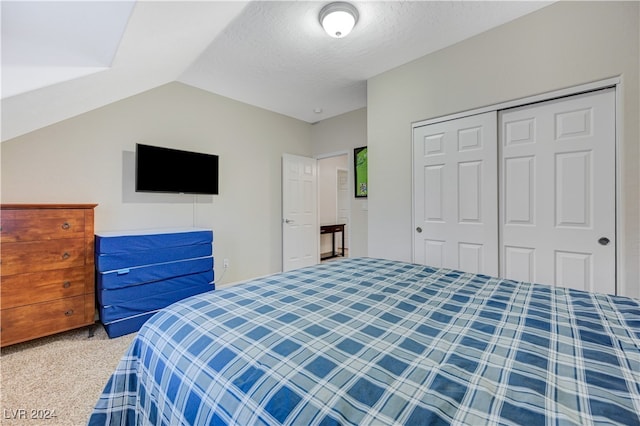 carpeted bedroom featuring a textured ceiling, a closet, and vaulted ceiling