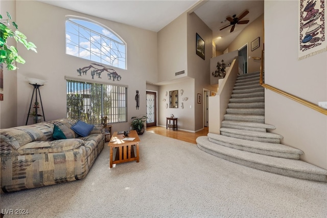 living room featuring wood-type flooring, a towering ceiling, and ceiling fan