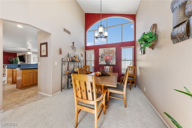 carpeted dining space featuring plenty of natural light, ceiling fan with notable chandelier, and high vaulted ceiling