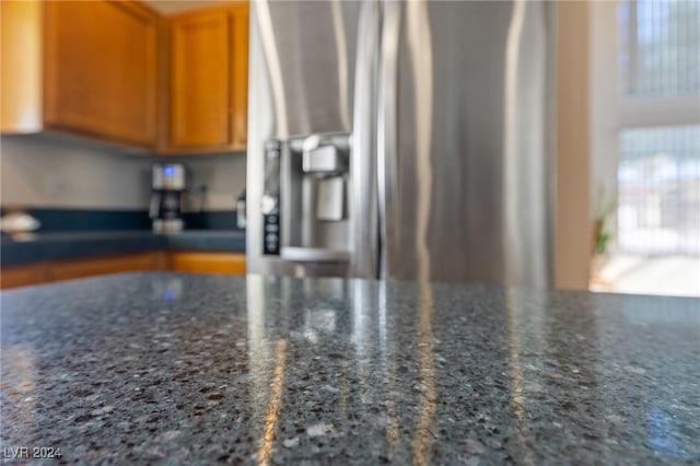 interior details with stainless steel fridge with ice dispenser and dark stone countertops