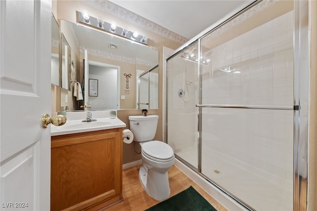 bathroom featuring a shower with door, vanity, wood-type flooring, and toilet