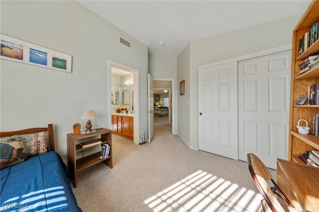 bedroom with ensuite bath, light carpet, and a closet