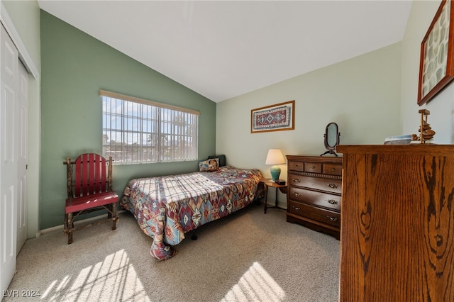 bedroom with light colored carpet, a closet, and lofted ceiling