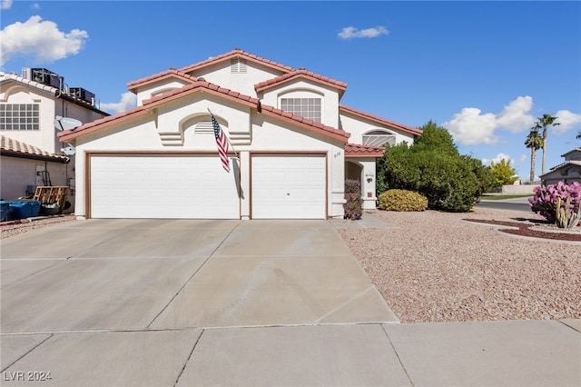 mediterranean / spanish-style house featuring concrete driveway, an attached garage, and a tiled roof