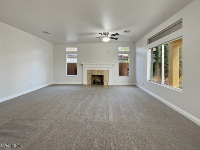 unfurnished living room featuring ceiling fan, a tiled fireplace, and carpet floors