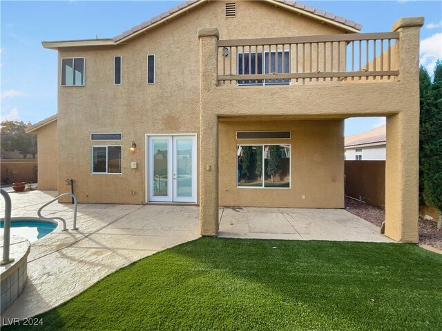 back of property featuring a fenced in pool, a patio, a lawn, and a balcony