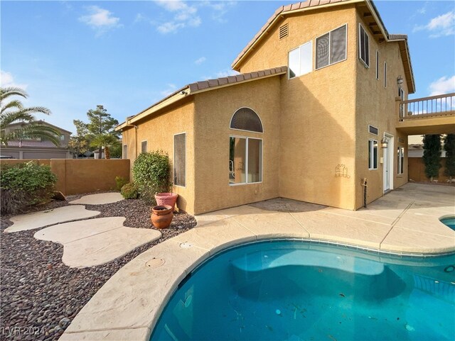 back of property with a patio and a fenced in pool