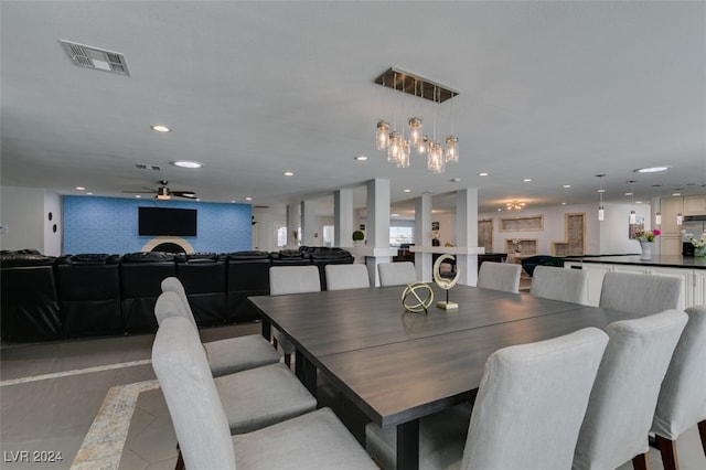 dining area featuring light tile patterned flooring, ceiling fan, and a large fireplace