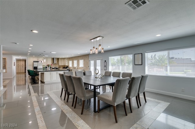 dining room with a chandelier, a textured ceiling, and light tile patterned floors