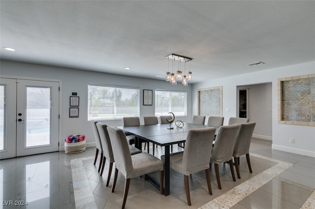 dining area featuring a chandelier, a textured ceiling, light tile patterned floors, and french doors