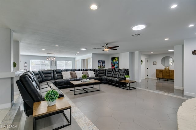 tiled living room with ceiling fan with notable chandelier