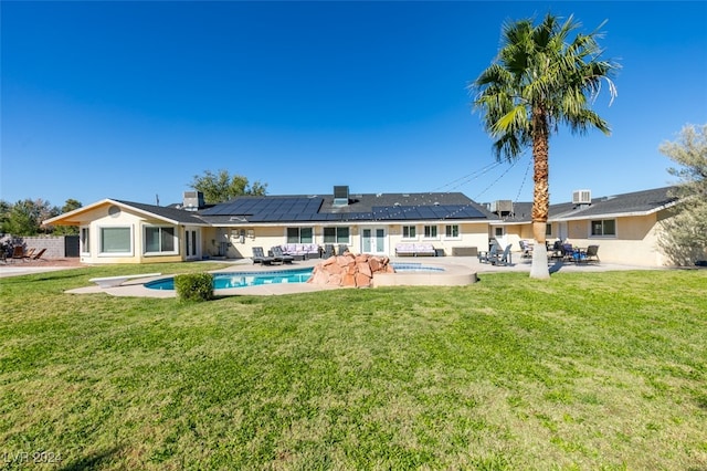 rear view of property featuring solar panels, a yard, and a patio area