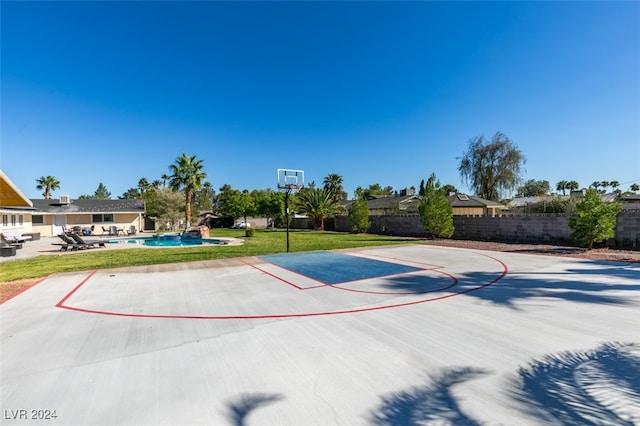 view of basketball court with a fenced in pool and a lawn