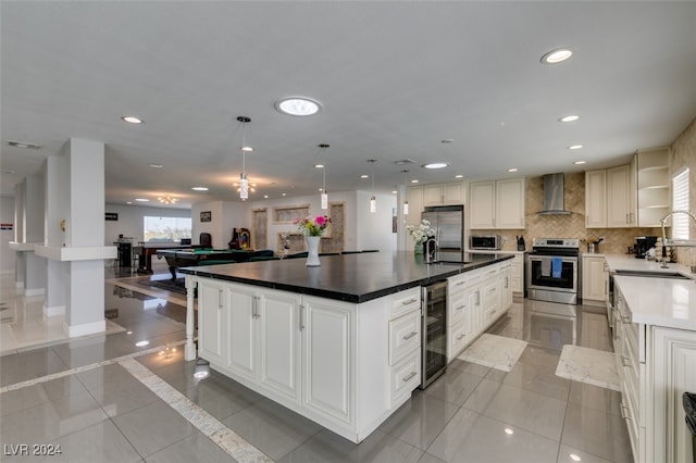 kitchen with light tile patterned flooring, stainless steel appliances, wall chimney range hood, a large island, and beverage cooler