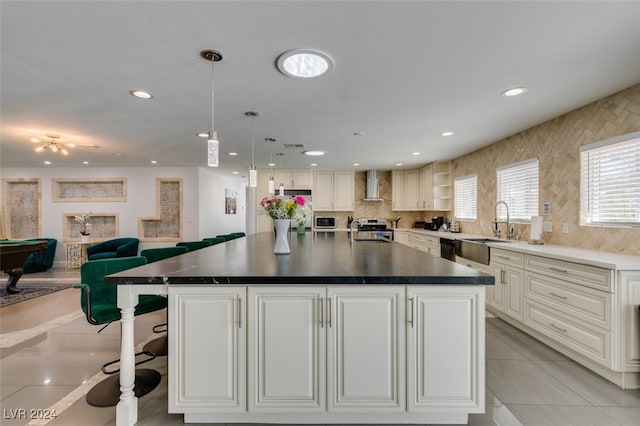 kitchen with stainless steel appliances, wall chimney range hood, and a kitchen island