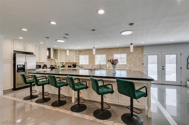 kitchen featuring stainless steel appliances, a healthy amount of sunlight, wall chimney range hood, and a breakfast bar area