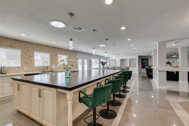 kitchen with decorative light fixtures, light tile patterned floors, sink, a kitchen breakfast bar, and a center island