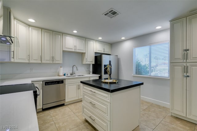 kitchen with stainless steel appliances, a kitchen island, light tile patterned floors, sink, and wall chimney exhaust hood