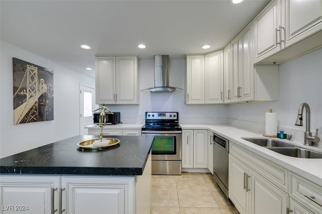 kitchen featuring stainless steel appliances, a center island, sink, wall chimney range hood, and white cabinetry